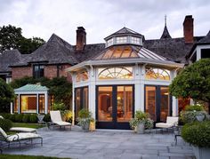 a large house with lots of windows and plants in the front lawn area at dusk