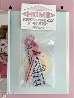 a pink and white keychain in a box with some tags attached to it