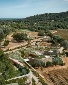 an aerial view of a stone building surrounded by trees and bushes in the middle of a field