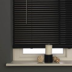 a white candle sitting on top of a window sill next to a black and white vase