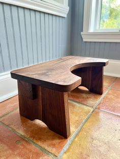 a wooden bench sitting on top of a tile floor next to a window in a room