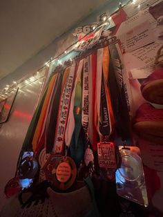 a bunch of medals are hanging on a wall with some lights in the back ground