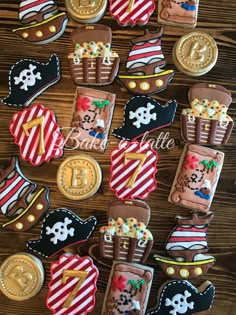 decorated pirate cookies are arranged on a wooden table with gold coins and other items in the shape of ships