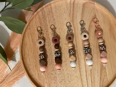 six wooden bead necklaces on a wood tray with greenery in the background