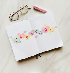 an open book with the word february written on it next to eyeglasses and a pen