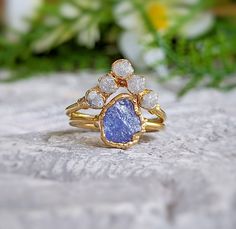 a close up of a ring on a rock with flowers in the backgroud