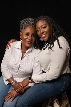 two women sitting on top of each other posing for the camera, with their arms around one another