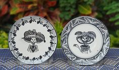 two black and white plates sitting on top of a table next to each other with designs on them