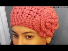 a woman wearing a pink crocheted hat with flowers on it's side