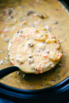 a ladle full of soup is being held up by a black handled spatula