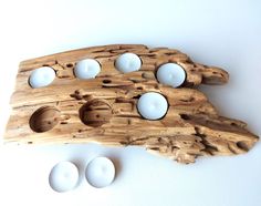 an object made out of wood with white balls on it and three holes in the middle