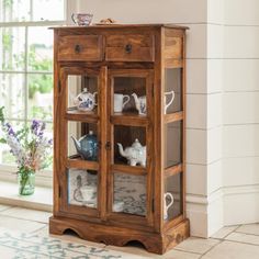 a wooden cabinet with glass doors and teapots on it