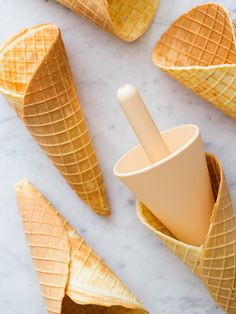 an ice cream cone with two scoops in it on a marble surface next to other cones