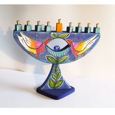 a ceramic menorah with birds and leaves on it's side, decorated with candles