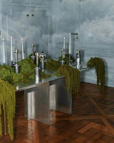 a table with candles and moss on it in a room that is decorated with clouds