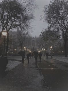 people walking down a sidewalk in the rain with their umbrellas open and lights on