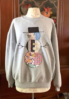 a gray sweater with a snowman on it sitting on top of a mannequin