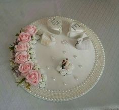 a wedding cake with pink roses and white shoes on the top is surrounded by pearls