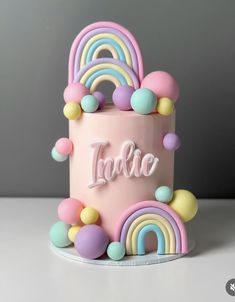 a pink cake with rainbows and balloons on it's side that says fabric