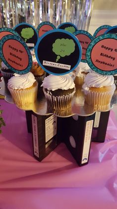 cupcakes are sitting on top of each other in front of a pink table cloth