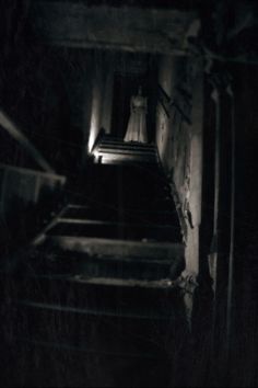 the stairs are lit up at night in this dark room with only one light on