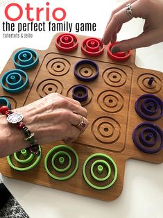 two people are playing an interactive game on a wooden board with colorful circles and rings