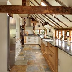 an open kitchen with white cabinets and wooden beams on the ceiling, along with marble counter tops