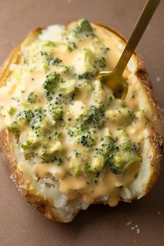 a piece of bread with broccoli and cheese on it next to a spoon