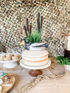 a table topped with cake and cupcakes next to a wall covered in leaves