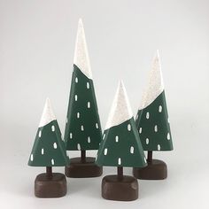 three green and white christmas trees sitting on top of each other in front of a white background