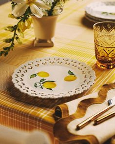 a table topped with plates and utensils on top of a yellow checkered table cloth