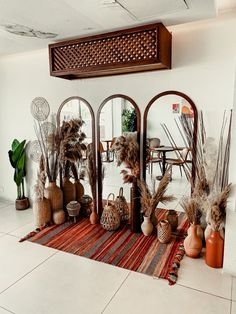 a room filled with vases and plants on top of a rug in front of a mirror