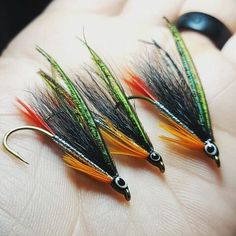 three orange and green flies sitting on top of each other in someone's hand