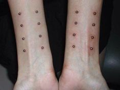 two people with small tattoos on their arms and legs, both have brown dots on them