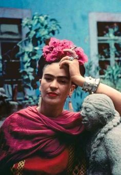 a woman with a flower in her hair standing next to a statue