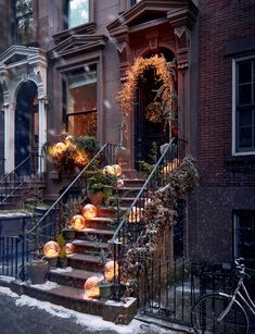 the steps are covered with pumpkins in front of an old brick building on a snowy day