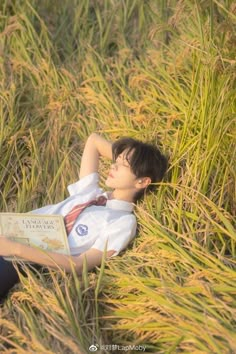 a boy laying in the grass reading a book