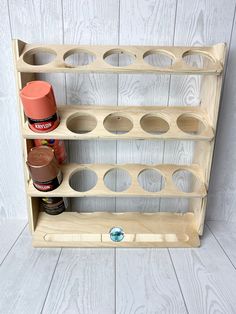 a wooden shelf with some jars and spices on it, against a white wood wall