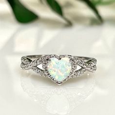 a white opal heart shaped ring with diamond accents