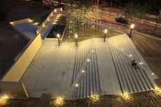 an aerial view of a park at night with lights on the ground and trees in the background