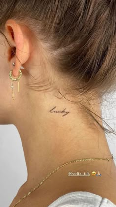 a woman with a small cross tattoo on her left side behind the ear is a gold chain