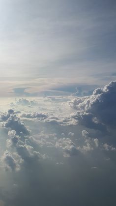 the view from an airplane looking down on some clouds and sun shining in the distance