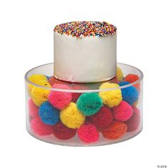 a white cake with colorful sprinkles in a clear container on a table