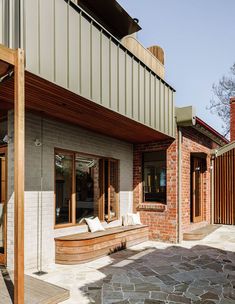 the outside of a house that is made out of brick and wood, with an outdoor seating area next to it