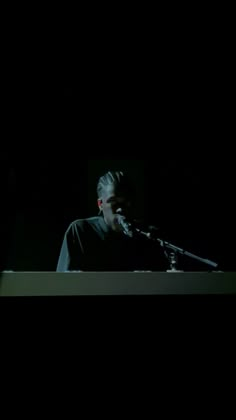 a man standing in front of a microphone on top of a table with a keyboard