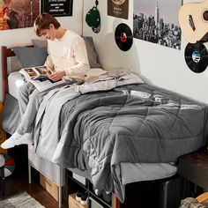 a young man sitting on top of a bed reading a book next to a guitar