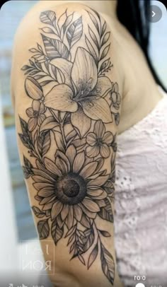 a woman's arm with flowers and leaves tattooed on the back of her shoulder