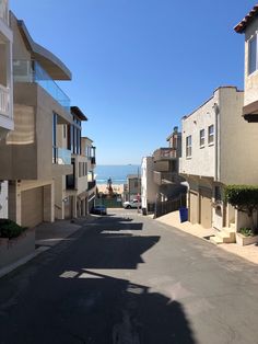 an empty street in front of some buildings with the ocean in the backround