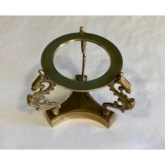 an antique brass clock with green glass eyes and ornate carvings on the front, sitting on a white background