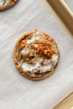 three cookies with white frosting and crumbs sitting on top of parchment paper